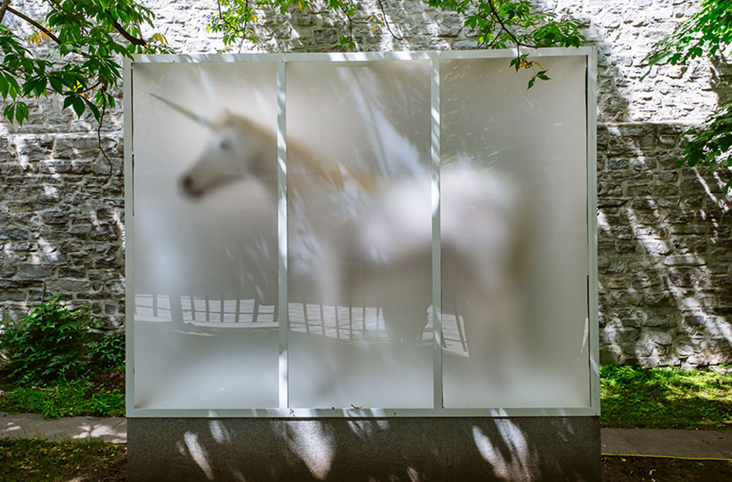 Une licorne enfermée dans une structure opaque. L'oeuvre est dans la rue.