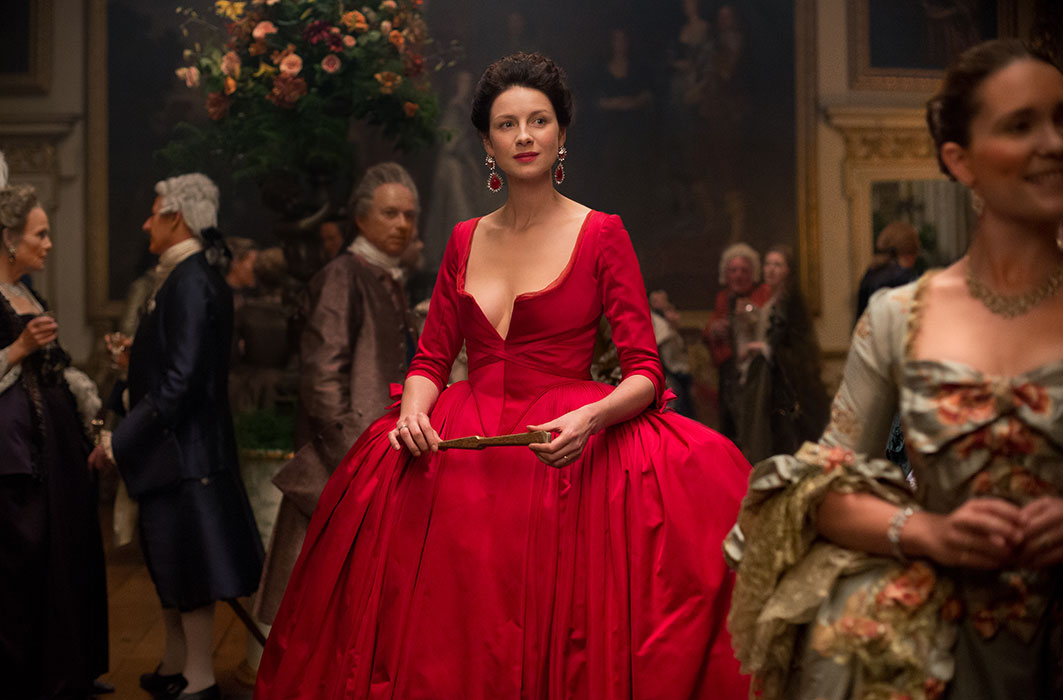 Claire en robe rouge dans le fictif château Wilton.
